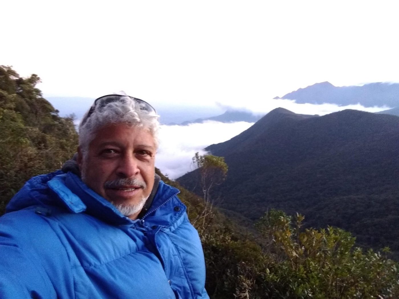Marcelo Costa on a mountain trail above Rio with clouds behind him